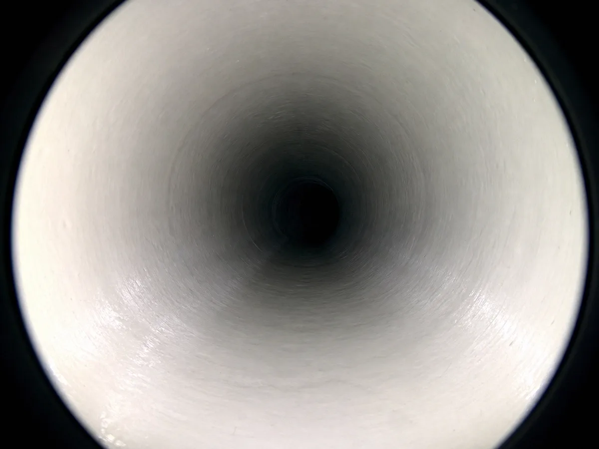 The view down a newly cured CIPP liner, its smooth white interior wall running the length of the pipe during the final camera pass.